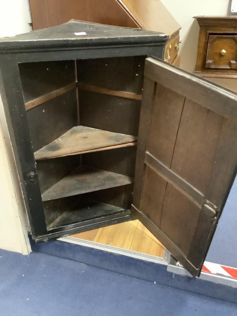 A late 18th century East Anglian lacquered hanging corner cupboard, painted with an interior scene with figures, width 51cm, depth 22cm, height 82cm